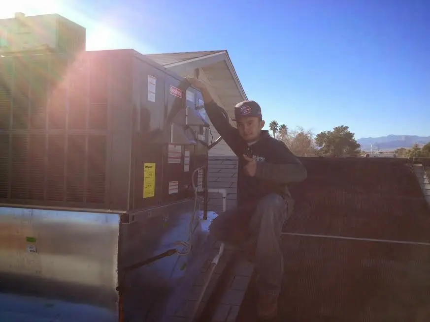 HVAC technician performing AC Tune-Up on a rooftop unit in South Ogden